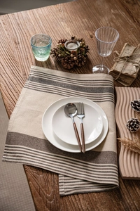 Flat lay of brown striped linen napkin with white ceramic plates on rustic wood