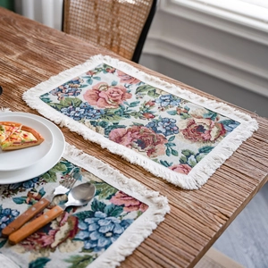 Floral jacquard table runner with ivory tassels on a dark wood dining table setup