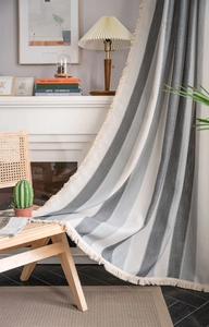 Detailed view of gray and white striped curtains with fringe trim in a cozy room