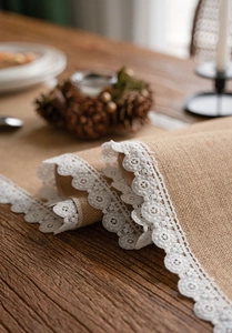 Detail of natural jute table runner with delicate white lace edges for rustic decor