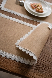 Close-up of natural jute table runner featuring intricate white lace embroidery edges