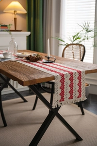Detail of red heart woven patterns on beige cotton linen table runner with tassels