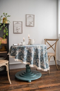 Detailed view of blue floral jacquard tablecloth with elegant cream fringe edges