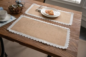 Set of two natural jute table mats with white lace edges on a rustic wooden dining table