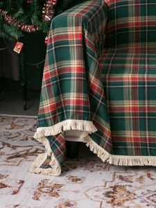 Close-up of green festive plaid throw blanket with red stripes and fringe detail