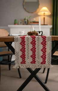 Detailed view of woven beige table runner with red hearts and decorative tassels