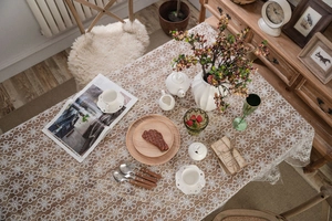Macro shot of white lace tablecloth with hollow daisy pattern on a rustic wooden table
