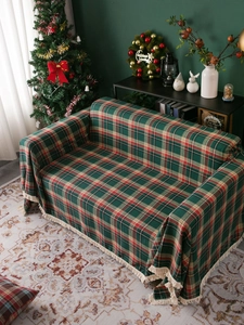 Close-up of green and red plaid Christmas throw blanket with tassels in festive setting