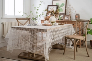 Close-up of white lace tablecloth with intricate floral embroidery on wooden table