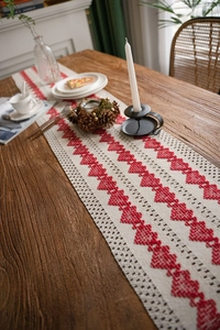 Close-up of cotton linen table runner with red heart woven pattern on dark wood table