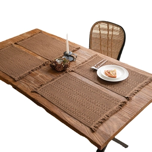 Set of 4 woven khaki table mats with decorative tassels on a wooden dining table