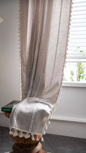 Détail du rideau en lin avec broderie géométrique blanche et bordure à franges