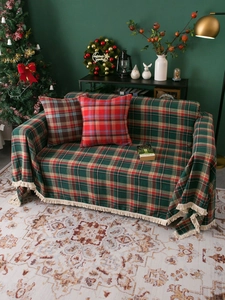 Detail of red and green plaid sofa throw with white fringe in a cozy Christmas setting