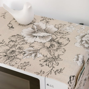 Detailed close-up of a vintage black floral linen dust cover on a white microwave oven