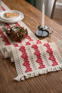 Detail of bohemian cotton table runner featuring red woven heart patterns and fringe