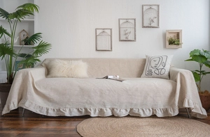 Detailed view of beige cotton linen sofa cover with elegant ruffled edges and rustic texture