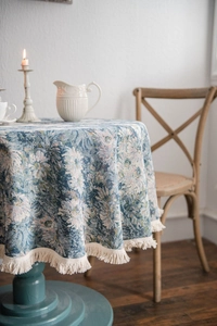 Detailed view of vintage blue floral jacquard tablecloth with delicate white cotton fringe