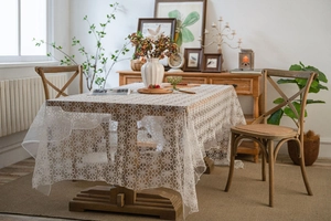 Close-up of white lace tablecloth featuring delicate six-petal floral crochet patterns
