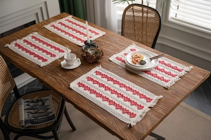 Close-up of woven cotton placemats featuring red heart patterns and fringe edges