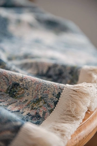 Close-up of blue floral jacquard tablecloth texture with elegant cream fringe tassels