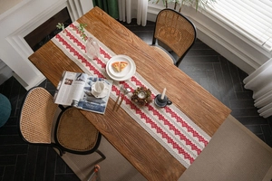Detailed close-up of a woven cotton linen table runner with red embroidered hearts and tassels