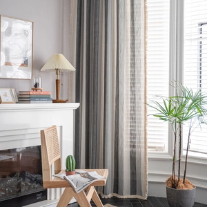 Neutral striped curtains with tassel fringe for a rustic living room window setting
