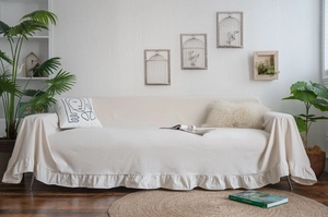 Detailed view of beige cream sofa cover featuring elegant ruffle edges and linen texture