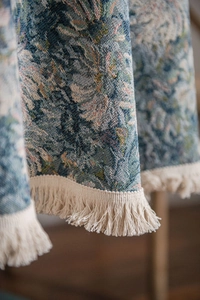 Detail of blue oil painting jacquard fabric with creamy white tassel fringe edge