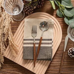 Retro stainless steel cutlery set with wood handles on a striped linen napkin and tray