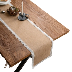 Rustic jute table runner with delicate white lace trim on an elegant wooden table