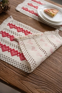 Detail of woven cotton linen table mat with red heart patterns and natural fringe