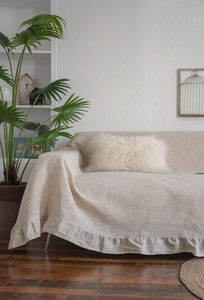Detail of beige linen sofa cover with ruffled edges in a minimalist interior setting