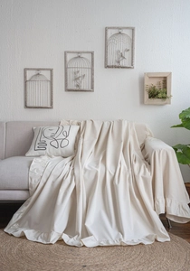Macro detail of creamy white ruffle edge sofa cover with natural linen fabric texture