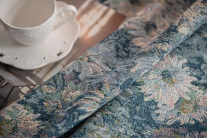 Close-up of thick blue jacquard fabric showing intricate floral texture and tassels