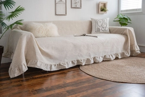 Close-up of beige linen sofa cover featuring elegant ruffle edges in a cozy home setting