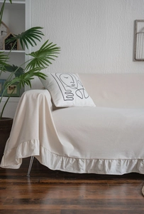 Detail of cream sofa cover featuring elegant ruffle edges and textured cotton fabric