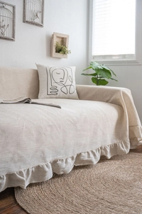 Detail view of beige linen sofa cover featuring elegant ruffled edges and natural texture