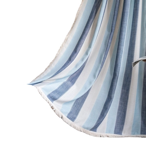 Vertical striped blue and white fabric curtain with decorative white fringe tassels