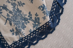 Detail of cotton linen curtain with blue rose print and wide crochet lace trim