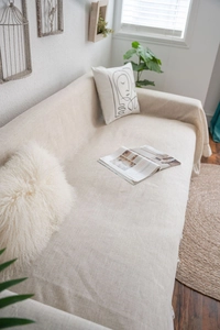 Detail of beige sofa cover showing premium linen texture and long tassel fringe edges