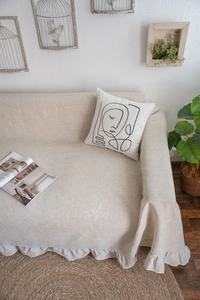 Macro detail of beige linen sofa cover with ruffles and a minimalist face pillow