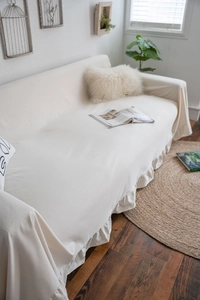 Detailed view of cream-colored sofa cover featuring ruffled edges and soft linen texture