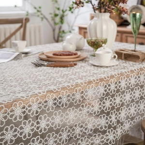 White floral lace tablecloth with embroidery pattern on a wooden dining table