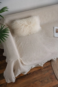 Close-up of cream linen sofa throw featuring elegant ruffle edges and textured fabric