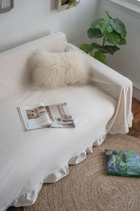 Detailed view of beige ruffled sofa cover with soft fabric textures and home decor