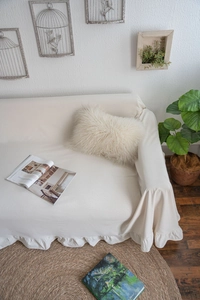 Close-up of cream sofa cover featuring elegant ruffled edges and soft linen texture