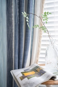 Détail de rideaux à rayures bleues et blanches avec pompons crème et texture lin