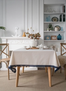 Detail of white cotton linen tablecloth featuring exquisite navy blue lace hollow edges