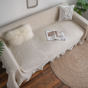 Beige cotton linen sofa cover with elegant ruffle edge in a natural minimalist living room
