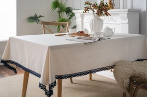 Detail of beige cotton linen tablecloth featuring navy blue crochet lace trim edges